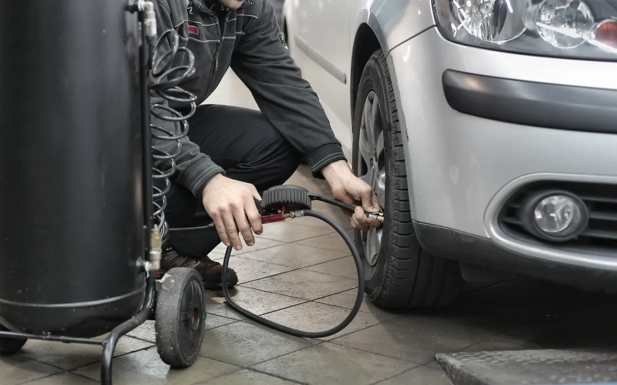 Mechanic carrying out a tyre safety inspection on a vehicle